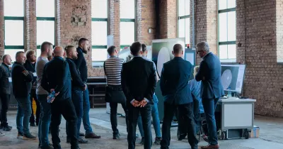 Grupa słuchaczy ogląda wyniki tomografii przemysłowej na monitorach podczas wydarzenia.